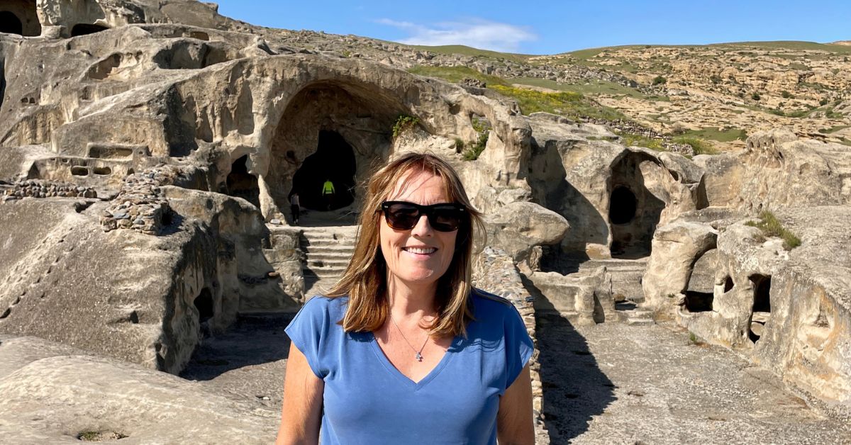 Woman stands in front of Uplistsiche Cave City in Georgia The Country. Stone Steps lead into the caves.