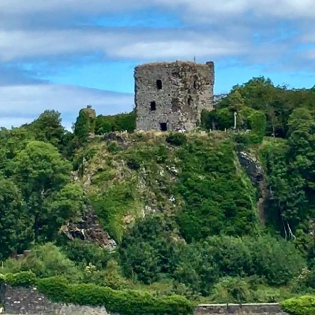 Ruins of Dunollie Castle in Oban perched on a small hill surrounded by trees.