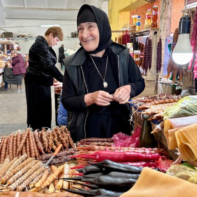 A market stall owner selling traditional Georgian candy which look like long candles.