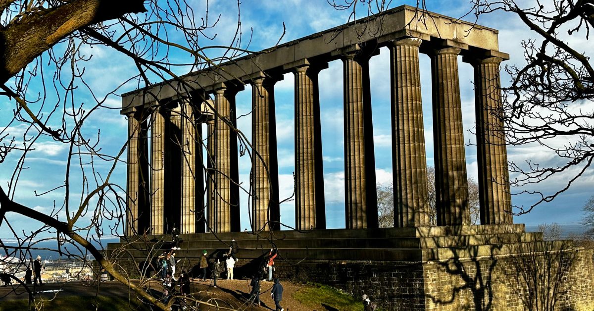 A set of stone pillars on top of a hill that people are viewing.