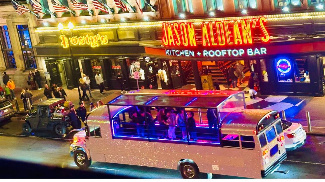 People being driven in a bus bar passing Jason Aldean’s Kitchen and Bar.