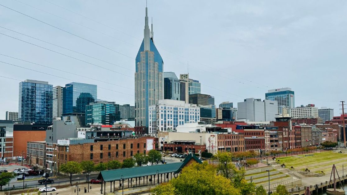 Skyline view of Nashville shows brown brick warehouse buildings and skyscrapers of the newer city.