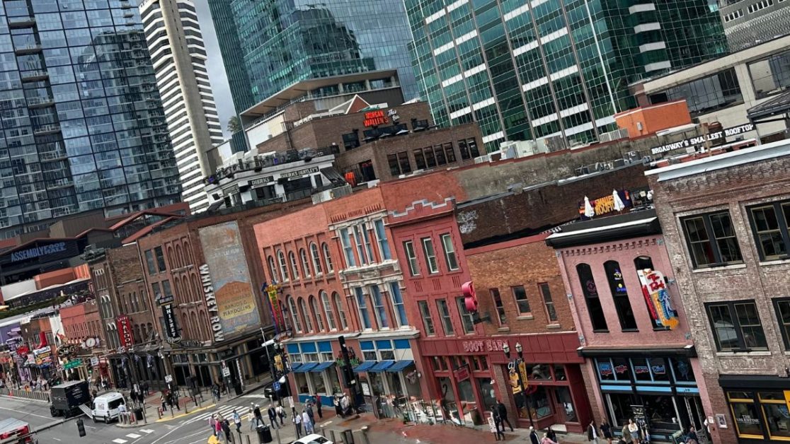 A rooftop view of Lower Broadway showing shops, restaurants and bars with people walking between them.